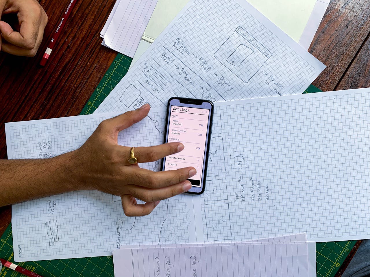 services-01 Hand holding smartphone over app design sketches on papers, top view.